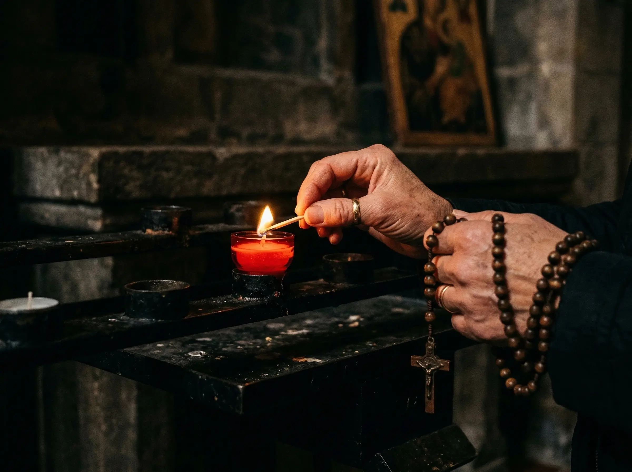 Votive candles burning quietly in a dim church, warm light against dark stone